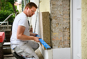 Sanieren &amp; Klimaschutz: Ein Handwerker bringt eine Dämmung aus Hanf an der Fassade an.