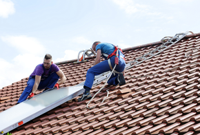 Installation Solarthermie: Männer schieben Kollektor übers Dach
